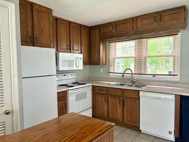 526 18th St, Jackson, MI 49203 - kitchen with white appliances, brown cabinetry, light countertops, and light tile patterned floors