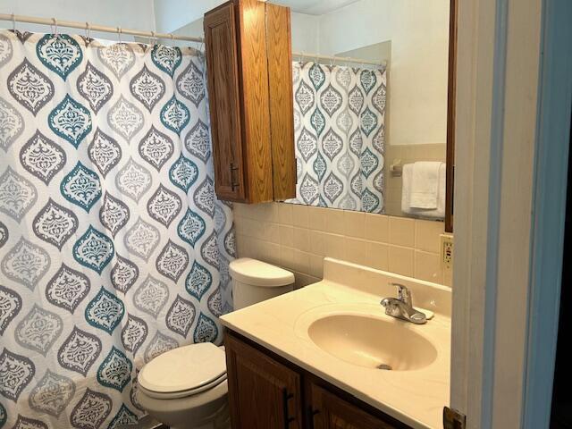 526 18th St, Jackson, MI 49203 - full bath featuring vanity, tile walls, tasteful backsplash, and curtained shower
