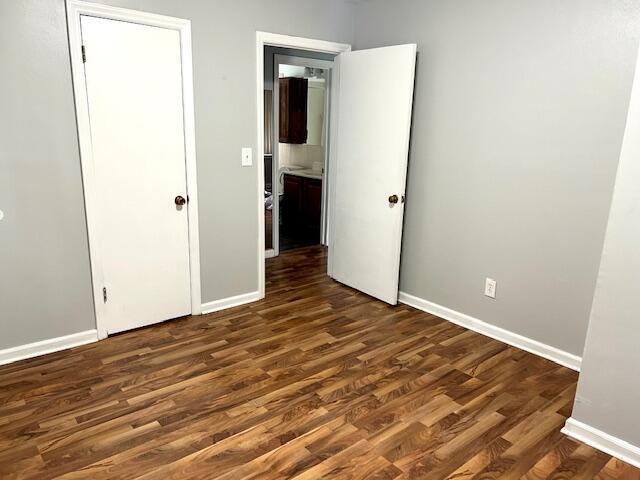 526 18th St, Jackson, MI 49203 - unfurnished bedroom with dark wood-style floors and baseboards