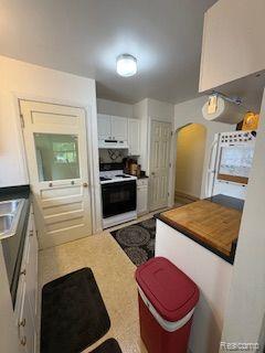 18598 Henry St, Melvindale, MI 48122 - kitchen with electric range oven, white cabinets, range hood, light countertops, and arched walkways