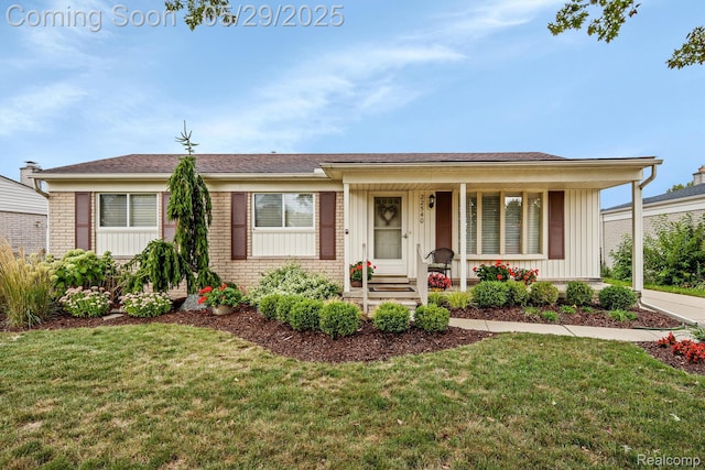 22540 Devonshire St, Woodhaven, MI 48183 - view of front of house featuring board and batten siding, covered porch, a front lawn, and brick siding