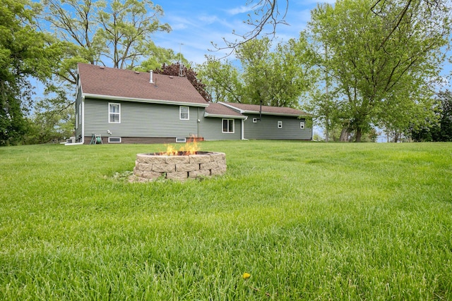 5778 Borland St, Sears, MI 49679 - rear view of property featuring an outdoor fire pit, a lawn, and a shingled roof