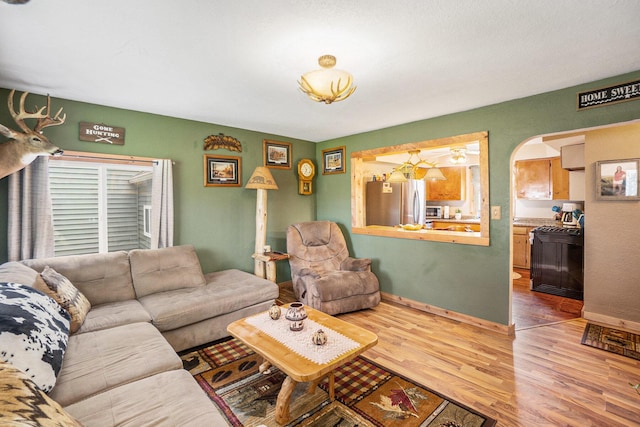 5778 Borland St, Sears, MI 49679 - living room featuring wood finished floors, arched walkways, and baseboards