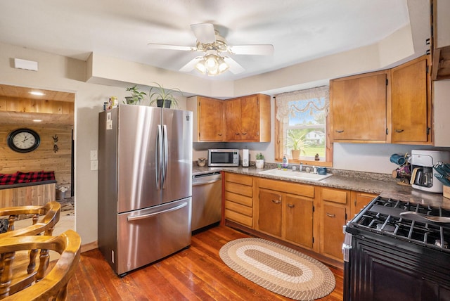 5778 Borland St, Sears, MI 49679 - kitchen featuring stainless steel appliances, a sink, dark wood finished floors, wood walls, and ceiling fan