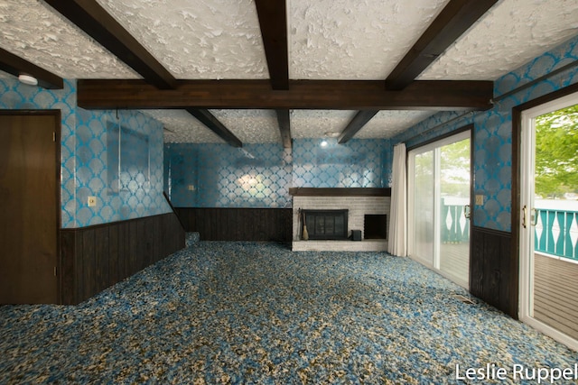 6221 Honeymoon Dr, Lakeview, MI 48850 - unfurnished living room featuring a wainscoted wall, carpet floors, wallpapered walls, beam ceiling, and a brick fireplace