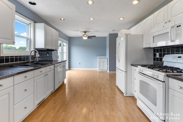 7300 Orchard View Dr NE, Rockford, MI 49341 - kitchen featuring white appliances, a sink, dark countertops, white cabinets, and light wood-style floors