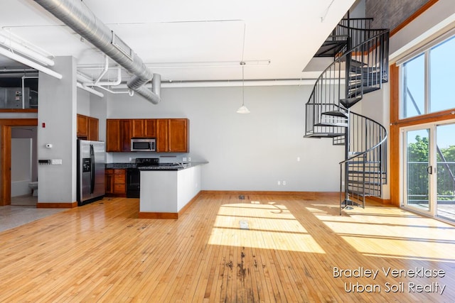 600 Broadway Ave NW Unit 414, Grand Rapids, MI 49504 - kitchen with appliances with stainless steel finishes, a high ceiling, light wood finished floors, a peninsula, and dark countertops