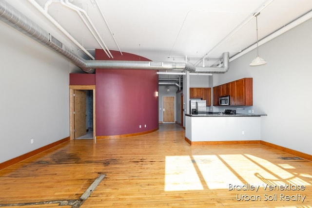 600 Broadway Ave NW Unit 414, Grand Rapids, MI 49504 - kitchen featuring stainless steel appliances, dark countertops, a towering ceiling, light wood-style floors, and hanging light fixtures