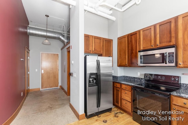 600 Broadway Ave NW Unit 414, Grand Rapids, MI 49504 - kitchen with appliances with stainless steel finishes, a towering ceiling, baseboards, brown cabinetry, and dark stone countertops