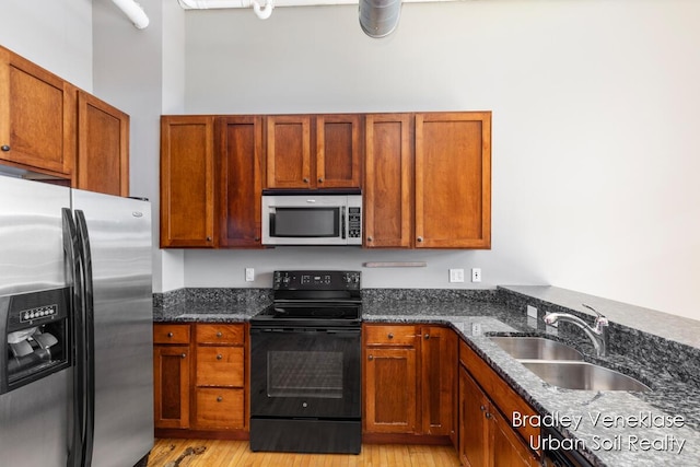600 Broadway Ave NW Unit 414, Grand Rapids, MI 49504 - kitchen featuring appliances with stainless steel finishes, a sink, dark stone countertops, and light wood-style floors