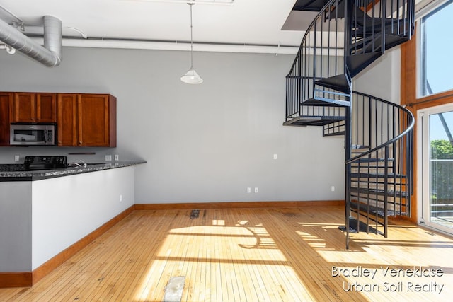 600 Broadway Ave NW Unit 414, Grand Rapids, MI 49504 - kitchen with stainless steel microwave, dark countertops, light wood-style flooring, and brown cabinetry
