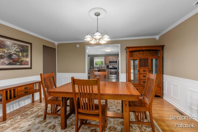 5826 W 124th St, Grant, MI 49327 - dining area with ornamental molding, a chandelier, light wood finished floors, and a wainscoted wall