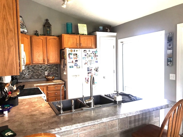 5883 Thistlewood Ave, Scotts, MI 49088 - kitchen featuring white appliances, tasteful backsplash, a peninsula, brown cabinets, and vaulted ceiling