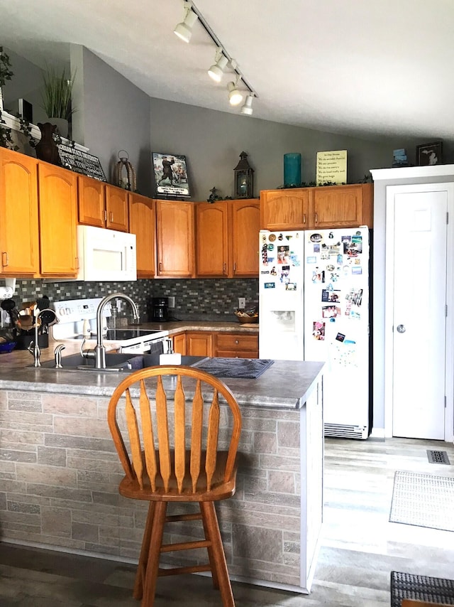 5883 Thistlewood Ave, Scotts, MI 49088 - kitchen featuring white appliances, track lighting, vaulted ceiling, decorative backsplash, and brown cabinets