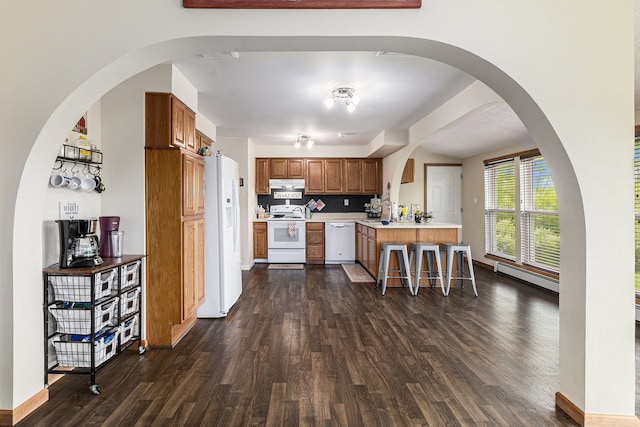 1977 Shipman Rd, Oxford, MI 48371 - kitchen featuring white appliances, dark wood-style flooring, brown cabinetry, under cabinet range hood, and a peninsula