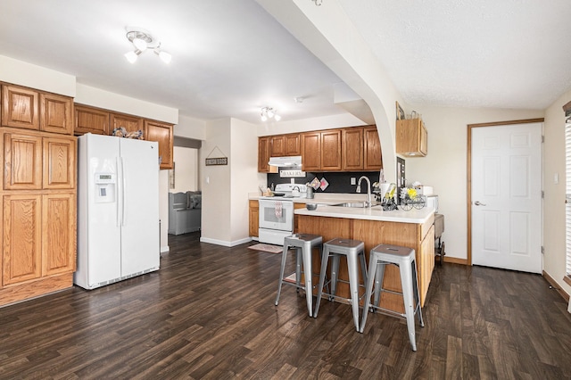 1977 Shipman Rd, Oxford, MI 48371 - kitchen with white appliances, a sink, a peninsula, a breakfast bar area, and dark wood-style floors