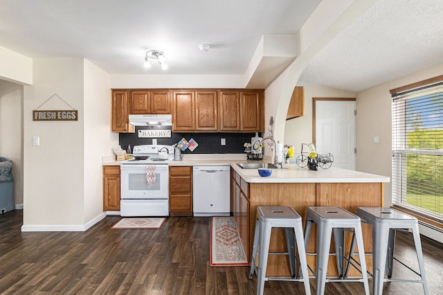 1977 Shipman Rd, Oxford, MI 48371 - kitchen featuring white appliances, a sink, under cabinet range hood, a peninsula, and brown cabinetry