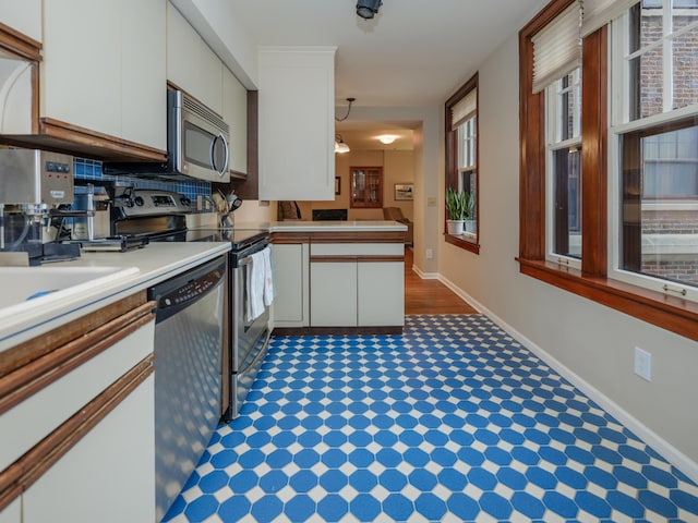 471 W S St Unit 207, Kalamazoo, MI 49007 - kitchen featuring stainless steel appliances, white cabinetry, a peninsula, light countertops, and baseboards