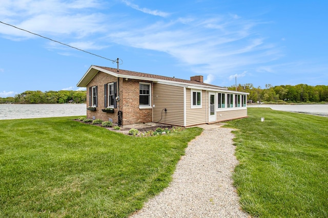 7394 N Keating Dr, Walkerville, MI 49459 - view of front of property featuring a front yard, a chimney, brick siding, and a water view