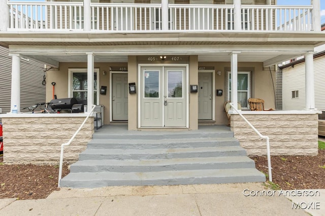407 11th St NW Unit 409, Grand Rapids, MI 49504 - view of exterior entry featuring a porch, stucco siding, and a balcony