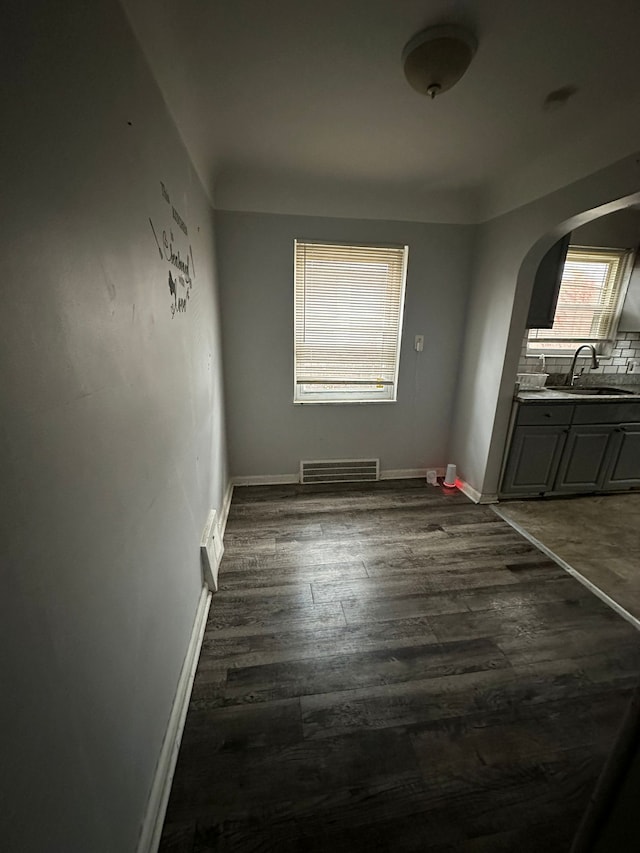 8603 Whitcomb St, Detroit, MI 48228 - unfurnished dining area with arched walkways, a sink, dark wood-style flooring, and baseboards
