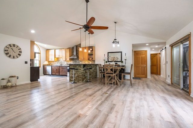 2363 Sundance Rdg, Howell, MI 48843 - kitchen featuring wall chimney exhaust hood, stainless steel dishwasher, vaulted ceiling, a ceiling fan, and a kitchen breakfast bar