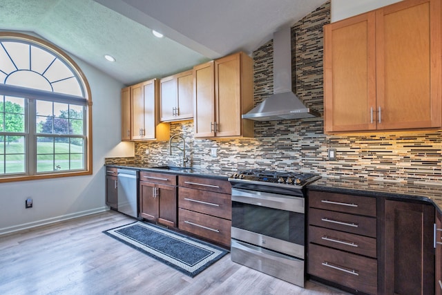 2363 Sundance Rdg, Howell, MI 48843 - kitchen with appliances with stainless steel finishes, a sink, vaulted ceiling, wall chimney range hood, and light wood-style flooring