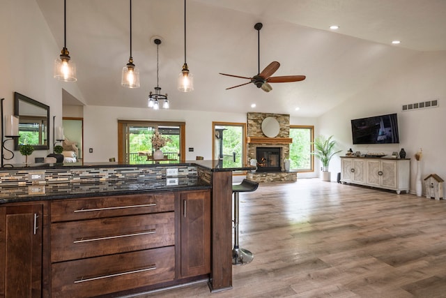 2363 Sundance Rdg, Howell, MI 48843 - kitchen featuring lofted ceiling, a ceiling fan, a kitchen breakfast bar, a fireplace, and wood finished floors