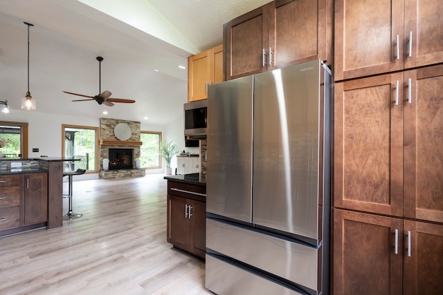 2363 Sundance Rdg, Howell, MI 48843 - kitchen with stainless steel appliances, vaulted ceiling, ceiling fan, plenty of natural light, and a stone fireplace