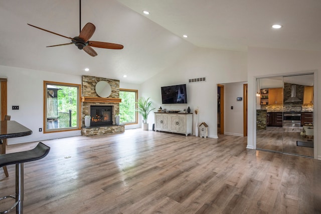 2363 Sundance Rdg, Howell, MI 48843 - living area featuring a ceiling fan, a stone fireplace, high vaulted ceiling, wood finished floors, and recessed lighting