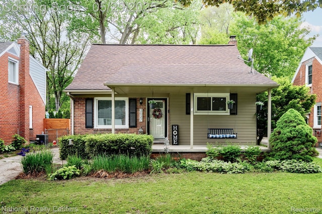 3027 Ferris Ave, Royal Oak, MI 48073 - view of front facade with a porch, a chimney, brick siding, central AC, and roof with shingles