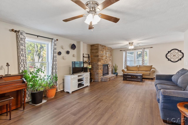 10623 Springville Hwy, Onsted, MI 49265 - living area with ceiling fan, wood finished floors, a stone fireplace, and a textured ceiling