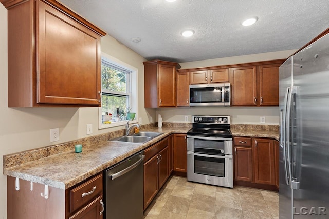 10623 Springville Hwy, Onsted, MI 49265 - kitchen featuring appliances with stainless steel finishes, a sink, a textured ceiling, brown cabinetry, and recessed lighting