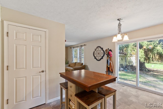 10623 Springville Hwy, Onsted, MI 49265 - dining room featuring stone finish flooring, a chandelier, a textured ceiling, and baseboards