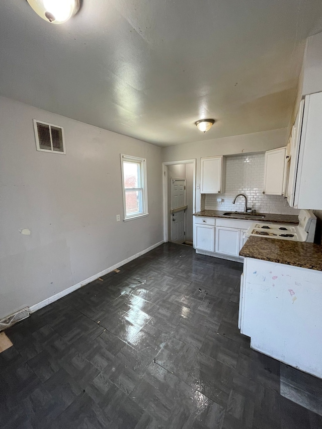 16500 Eastburn St, Detroit, MI 48205 - kitchen featuring dark countertops, electric range, a sink, baseboards, and white cabinetry