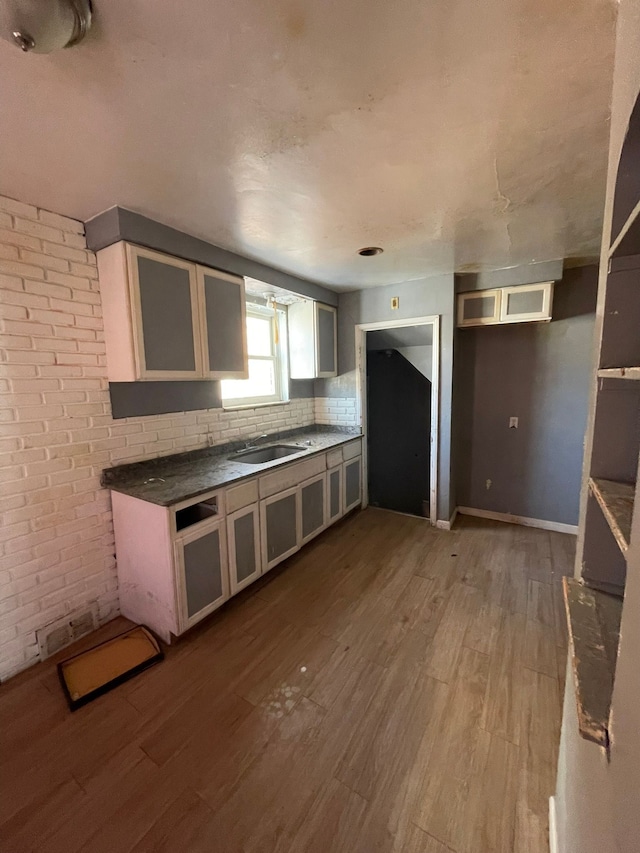 10952 Peerless St, Detroit, MI 48224 - kitchen with wood finished floors, glass insert cabinets, dark countertops, and a sink