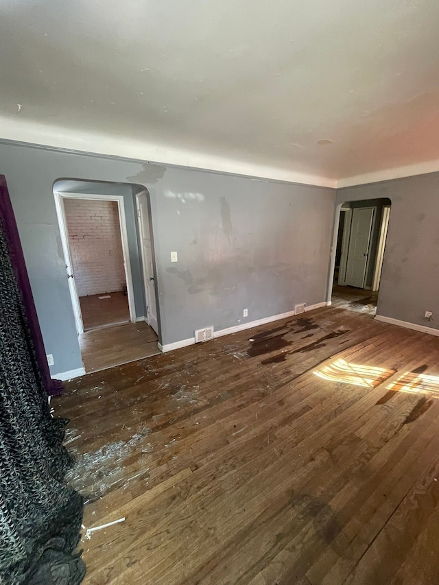 10952 Peerless St, Detroit, MI 48224 - empty room with arched walkways, wood-type flooring, and baseboards