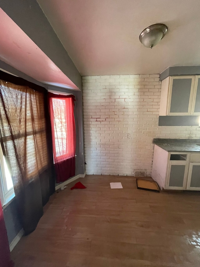 10952 Peerless St, Detroit, MI 48224 - kitchen with wood finished floors, brick wall, baseboards, and glass insert cabinets