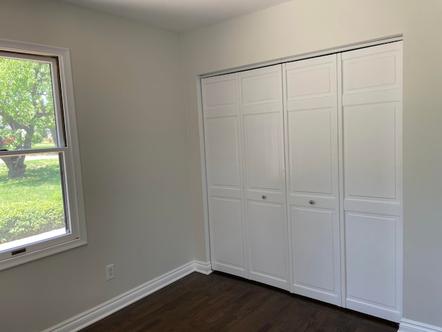 1659 Weymouth St, West Bloomfield, MI 48324 - unfurnished bedroom with multiple windows, dark wood-style floors, a closet, and baseboards