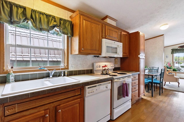 1797 Lawrence Dr, Bitely, MI 49309 - kitchen featuring white appliances, a sink, ornamental molding, brown cabinets, and wood finished floors