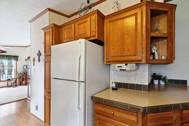 1797 Lawrence Dr, Bitely, MI 49309 - kitchen with freestanding refrigerator, brown cabinets, ornamental molding, wood finished floors, and a textured ceiling