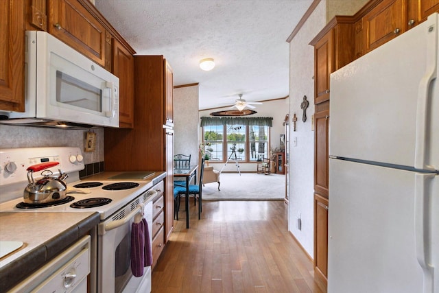 1797 Lawrence Dr, Bitely, MI 49309 - kitchen featuring white appliances, a ceiling fan, brown cabinetry, hardwood / wood-style floors, and a textured ceiling