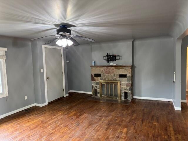 418 N Hemlock St, Evart, MI 49631 - unfurnished living room with a ceiling fan, a fireplace, wood finished floors, baseboards, and arched walkways
