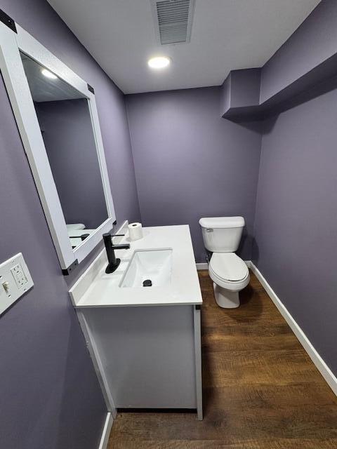 418 N Hemlock St, Evart, MI 49631 - half bathroom featuring toilet, vanity, wood finished floors, and baseboards