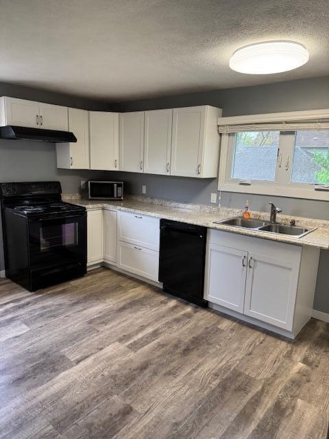 418 N Hemlock St, Evart, MI 49631 - kitchen with black appliances, a sink, under cabinet range hood, white cabinets, and a textured ceiling