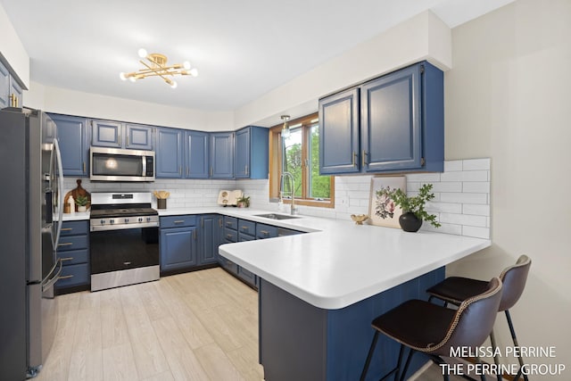7359 Cascade Woods Dr SE, Grand Rapids, MI 49546 - kitchen featuring appliances with stainless steel finishes, a sink, a peninsula, blue cabinets, and a breakfast bar