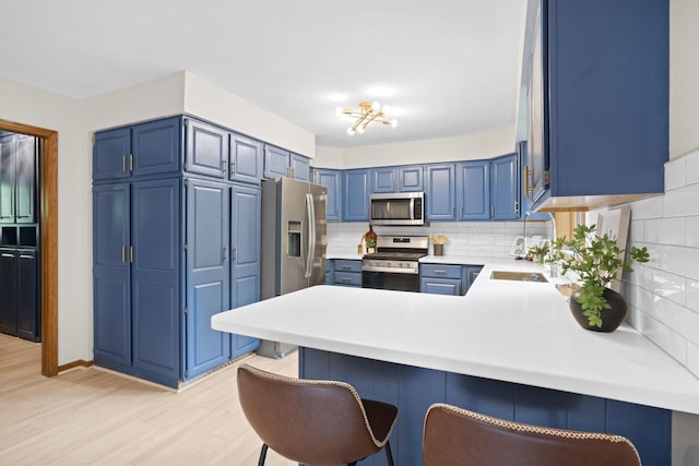 7359 Cascade Woods Dr SE, Grand Rapids, MI 49546 - kitchen with appliances with stainless steel finishes, blue cabinetry, a peninsula, and light countertops
