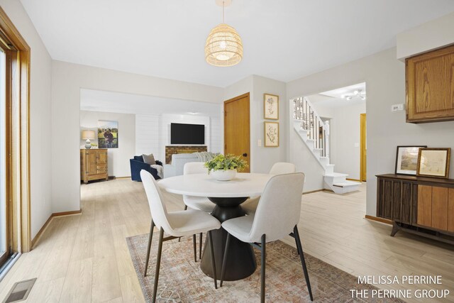 7359 Cascade Woods Dr SE, Grand Rapids, MI 49546 - dining room with stairway, light wood finished floors, a chandelier, and baseboards