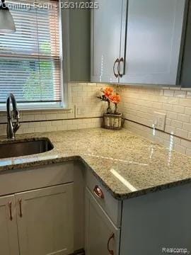 8441 Colgate St, Oak Park, MI 48237 - kitchen featuring a sink, decorative backsplash, and light stone countertops