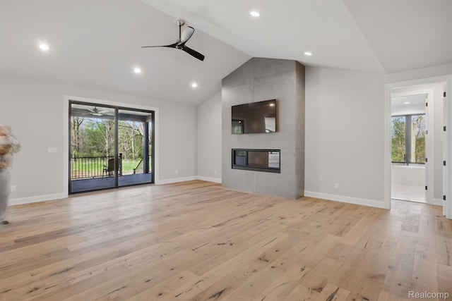 4030 Metamora Rdg, Metamora, MI 48455 - unfurnished living room featuring a ceiling fan, a tile fireplace, vaulted ceiling, light wood-type flooring, and healthy amount of natural light